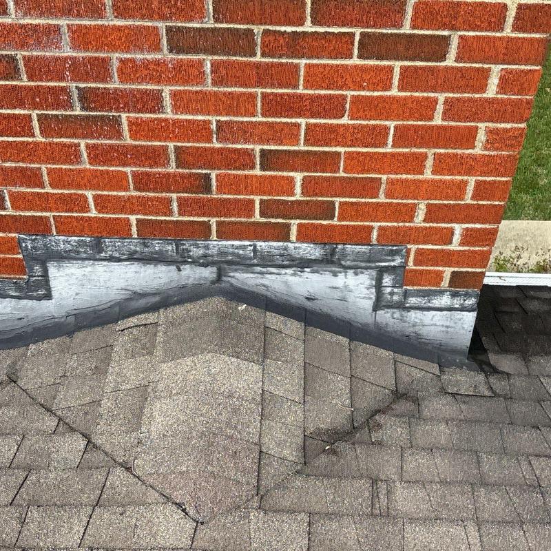 Roof flashing repair on shingle roof near brick wall