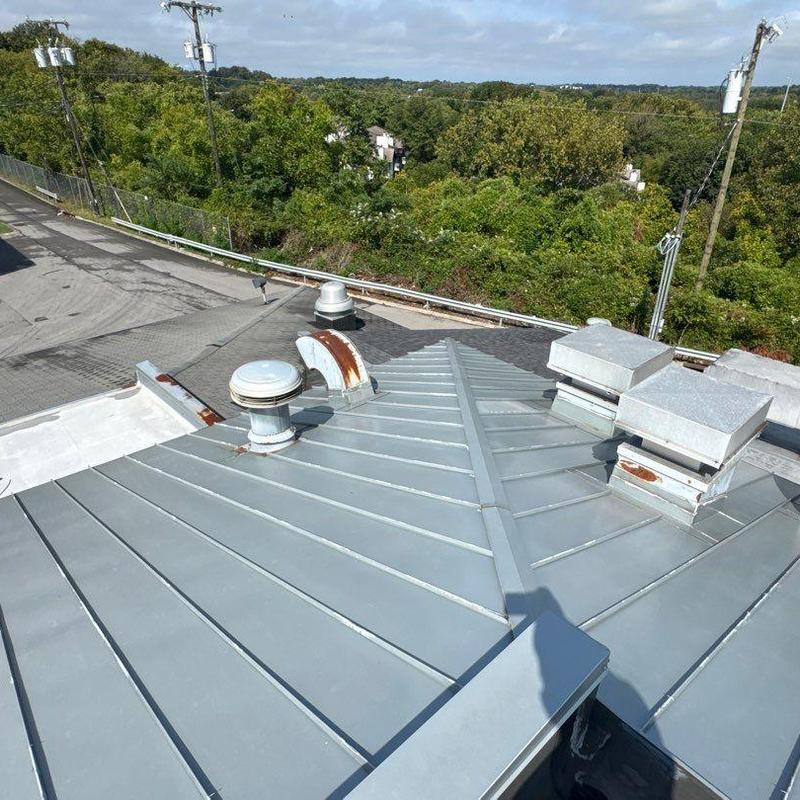Metal roof panels with rusted vent pipes and flashing