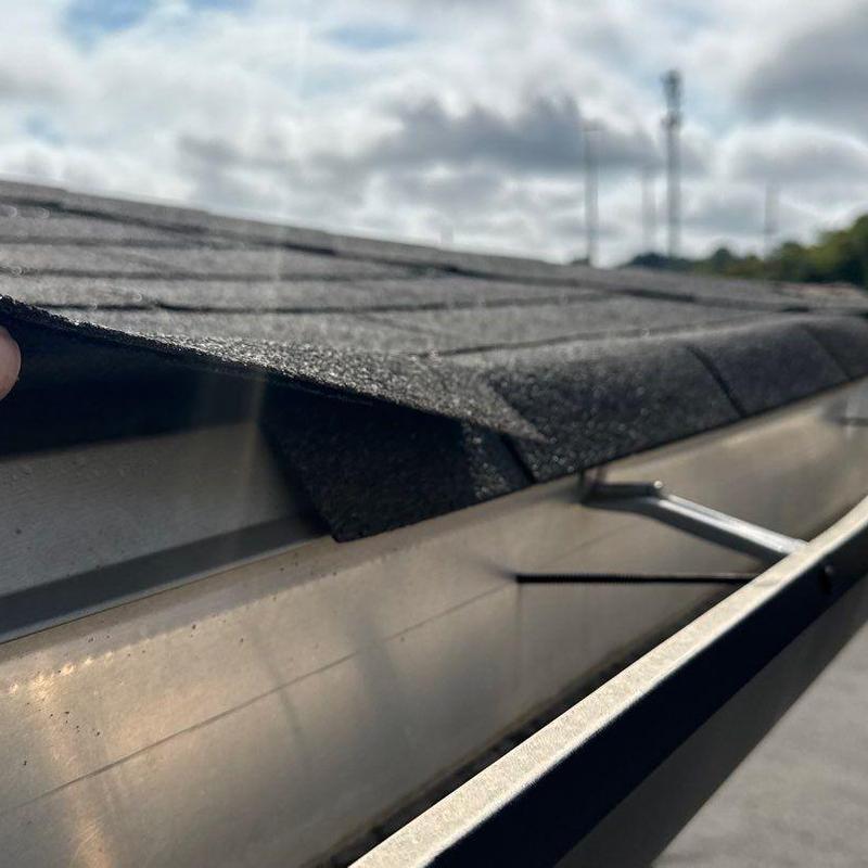 Asphalt shingle edge lifted above metal gutter system