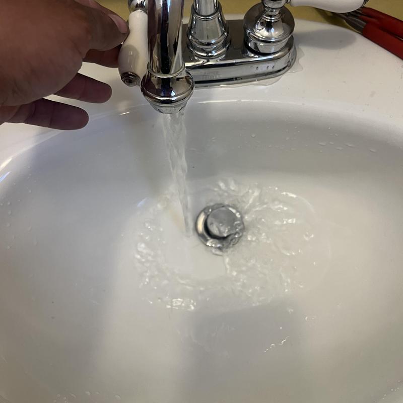 Bathroom faucet running water with hand adjusting handle