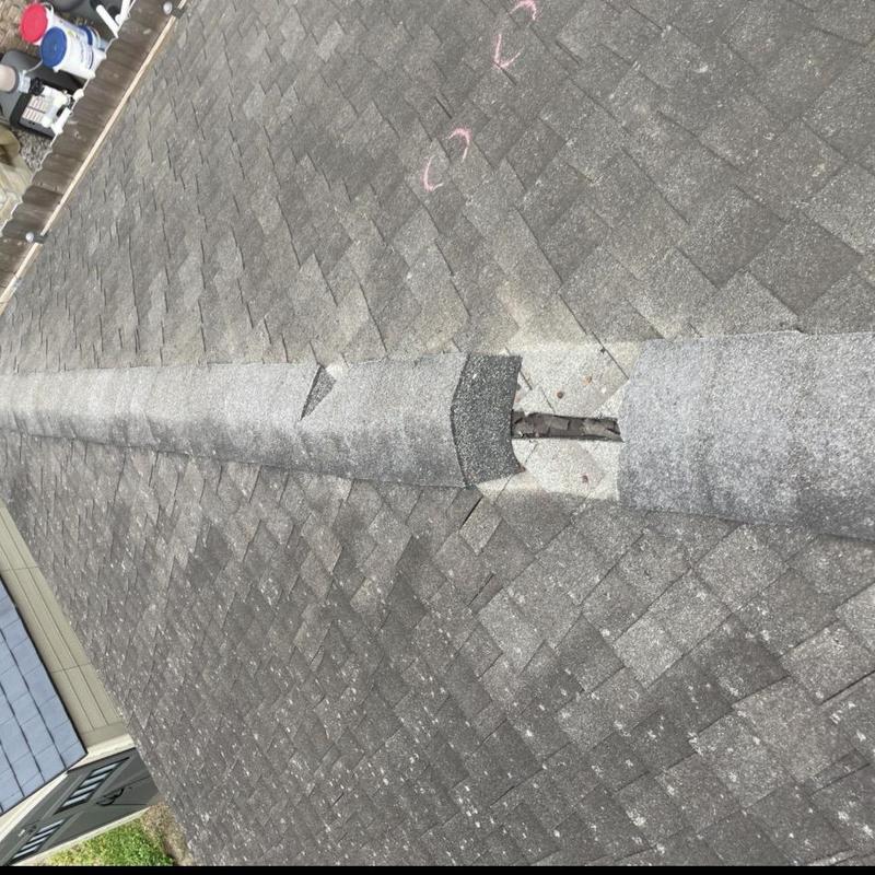 Asphalt shingle roof ridge with missing shingles
