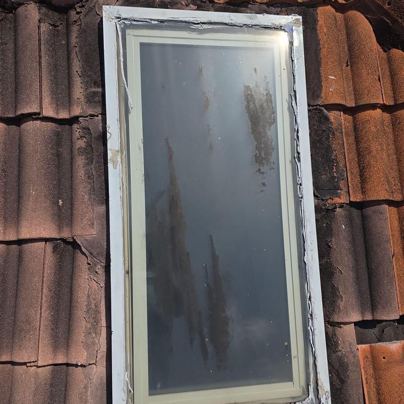 Skylight on aged damaged tile roof with sealant wear