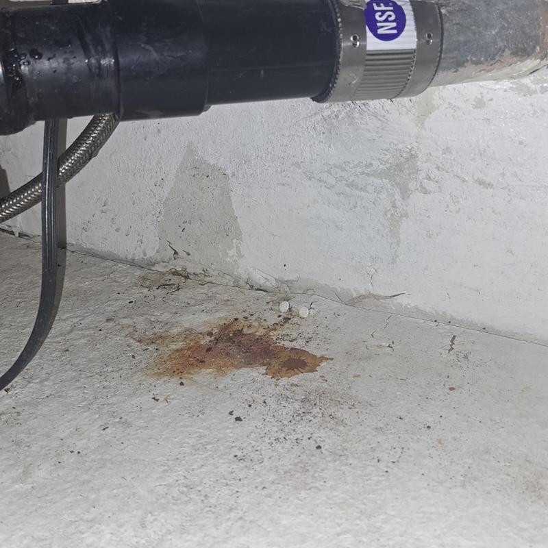 Kitchen drain pipe under sink with rust stain