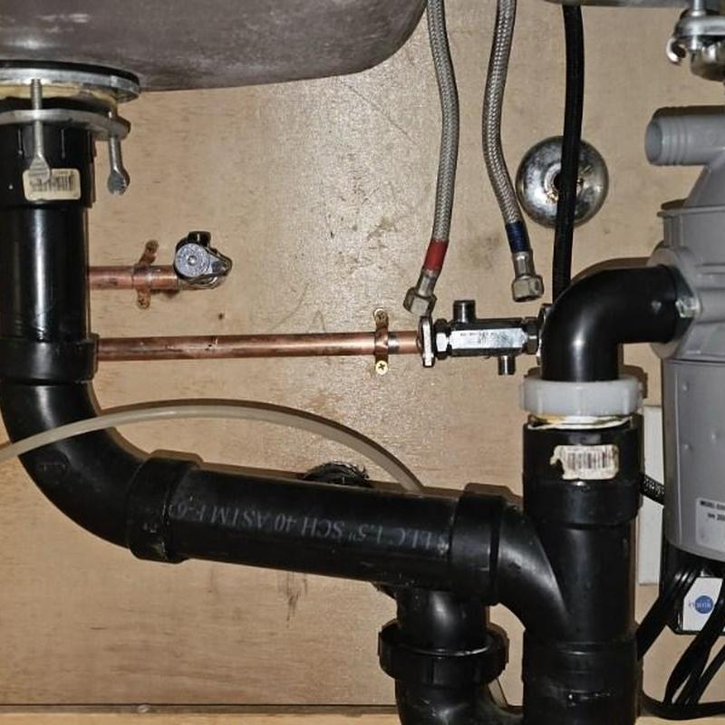 Copper water lines and black drain pipes under sink