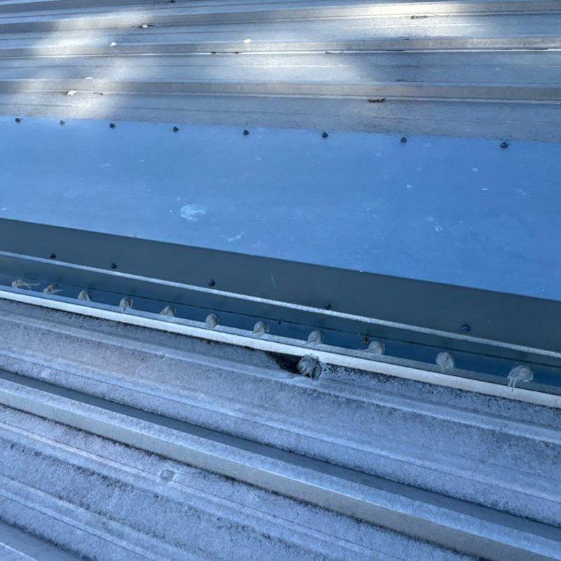 Metal roof ridge cap with hail damage and fasteners