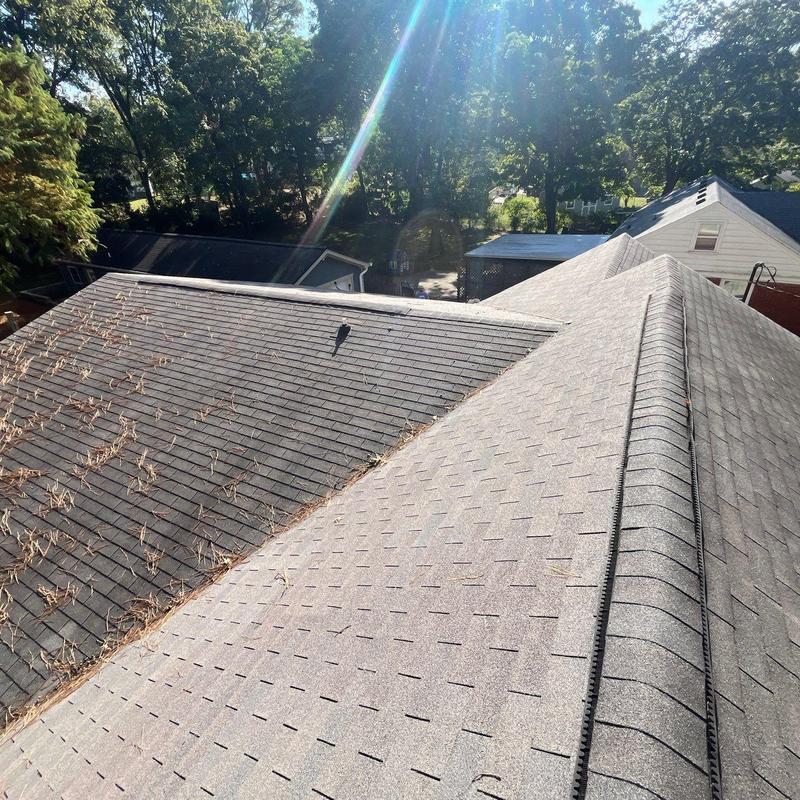 Asphalt shingle roof ridge with hail damage and debris