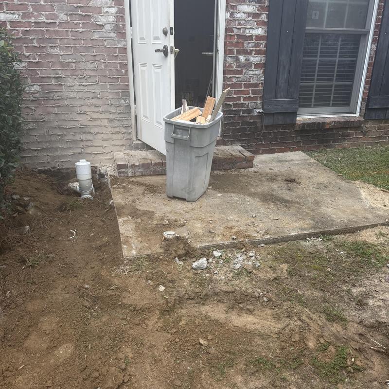Concrete patio demo with debris bin near house door
