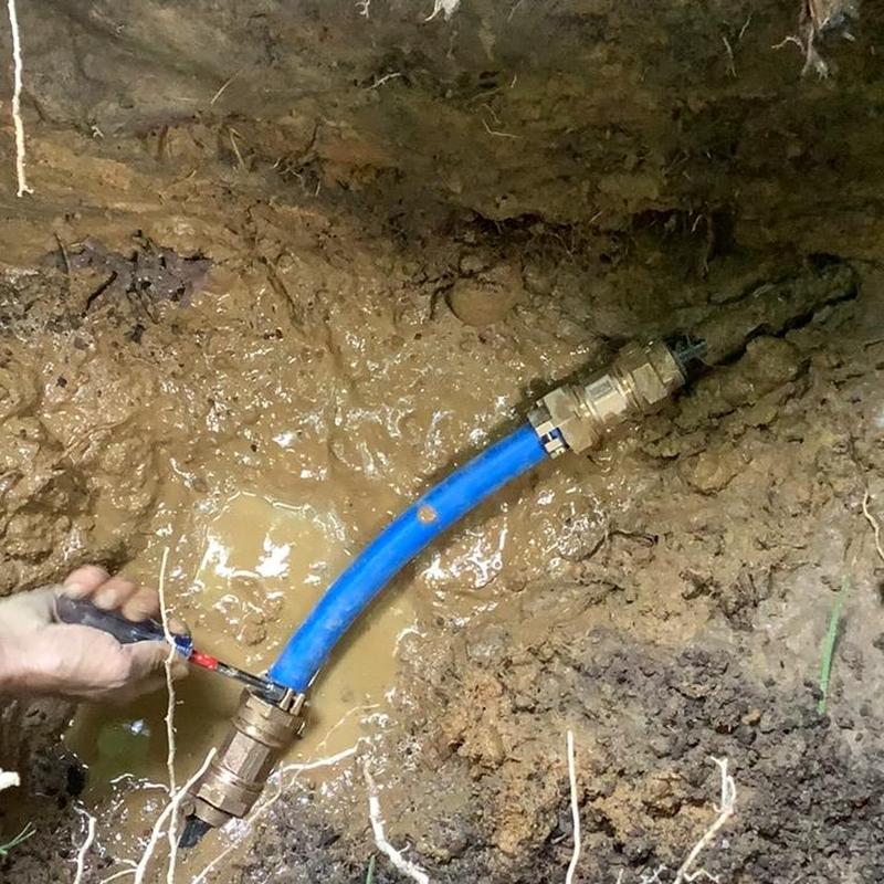 Main waterline with blue pipe repair in muddy trench Main waterline with blue pipe repair in muddy trench