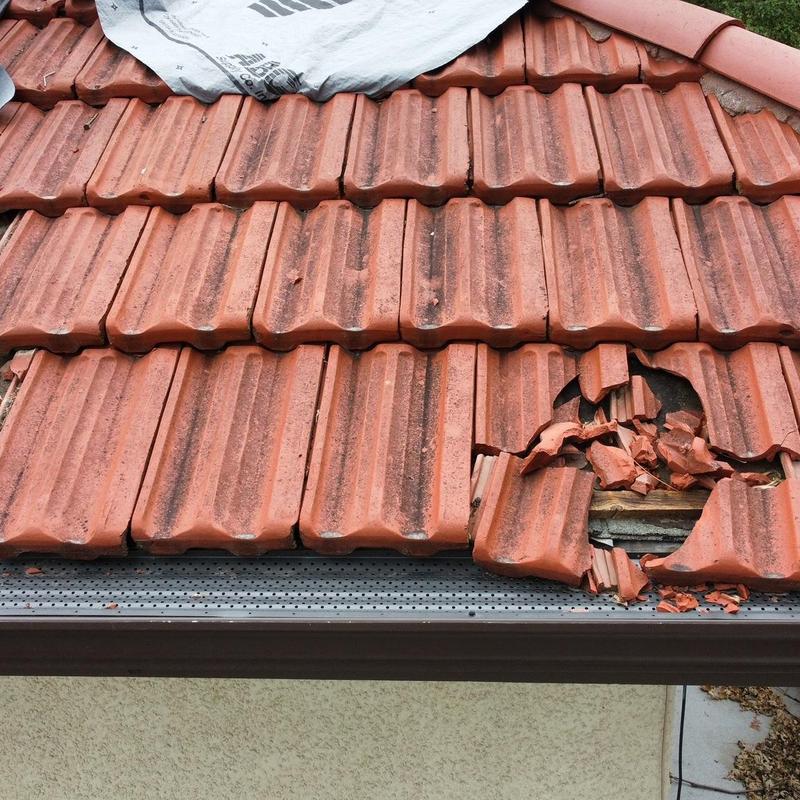 Historic clay tile roof with broken tiles near gutter
