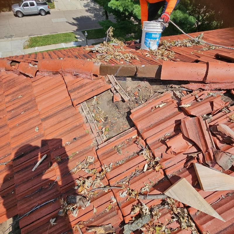 Historic clay tile roof with storm damage hole