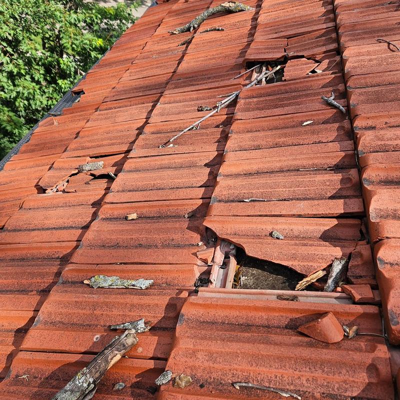 Clay tile roof with broken and missing tiles after storm damage