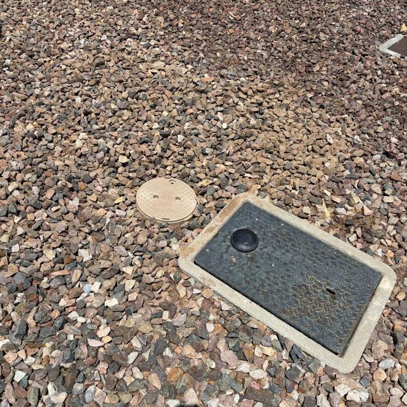 Water main access box and pressure regulator cover in gravel