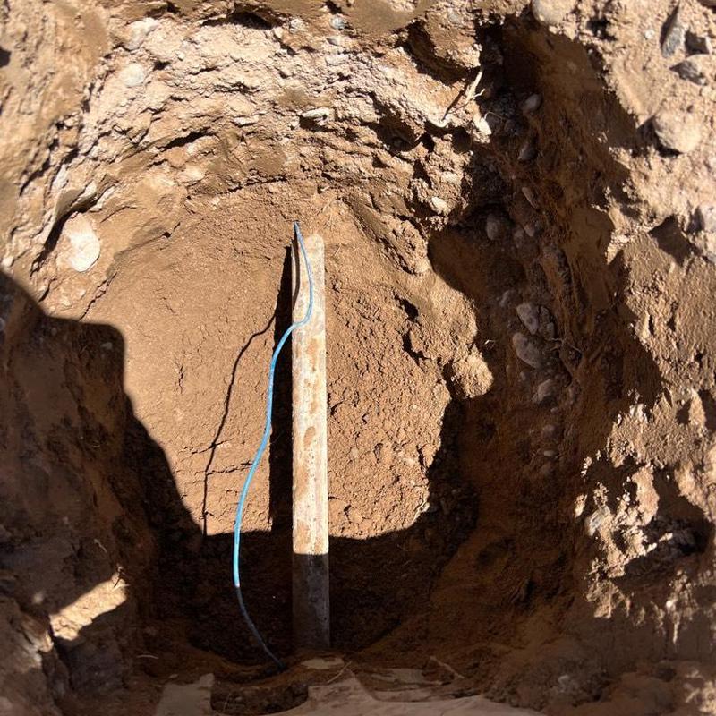 Water main excavation site with exposed pipe in dirt