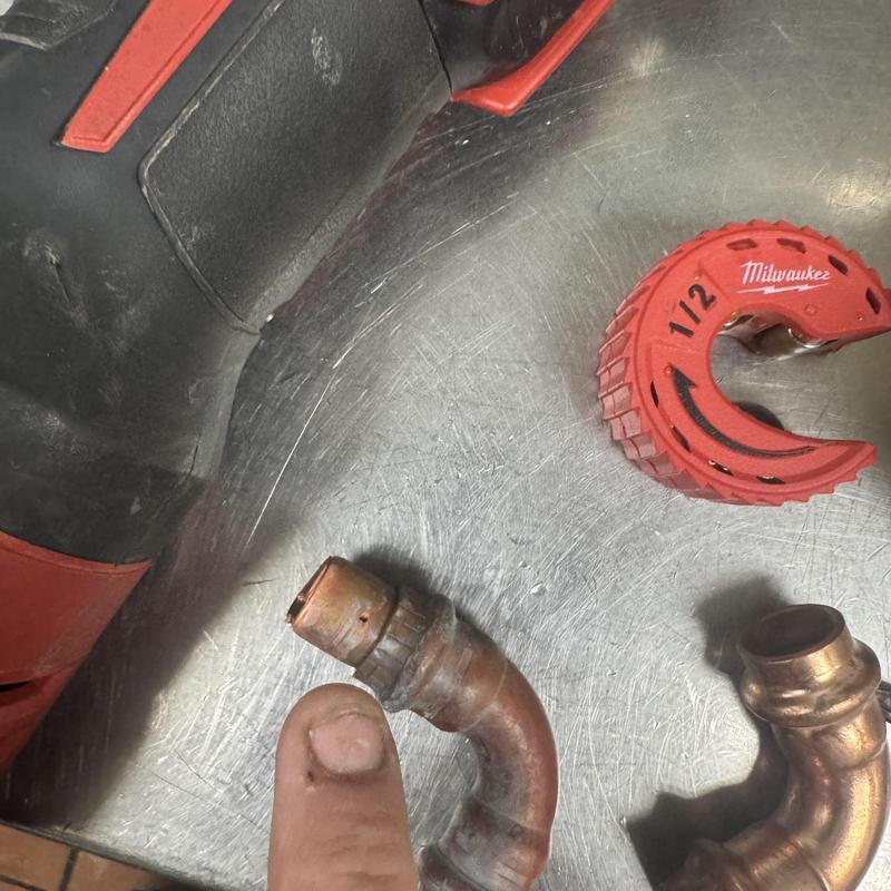Half-inch copper waterline with pinhole leak and pipe cutter Half-inch copper waterline with pinhole leak and pipe cutter