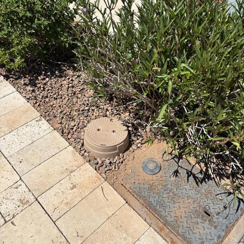 Pressure relief valve with tan access box beside curb stop