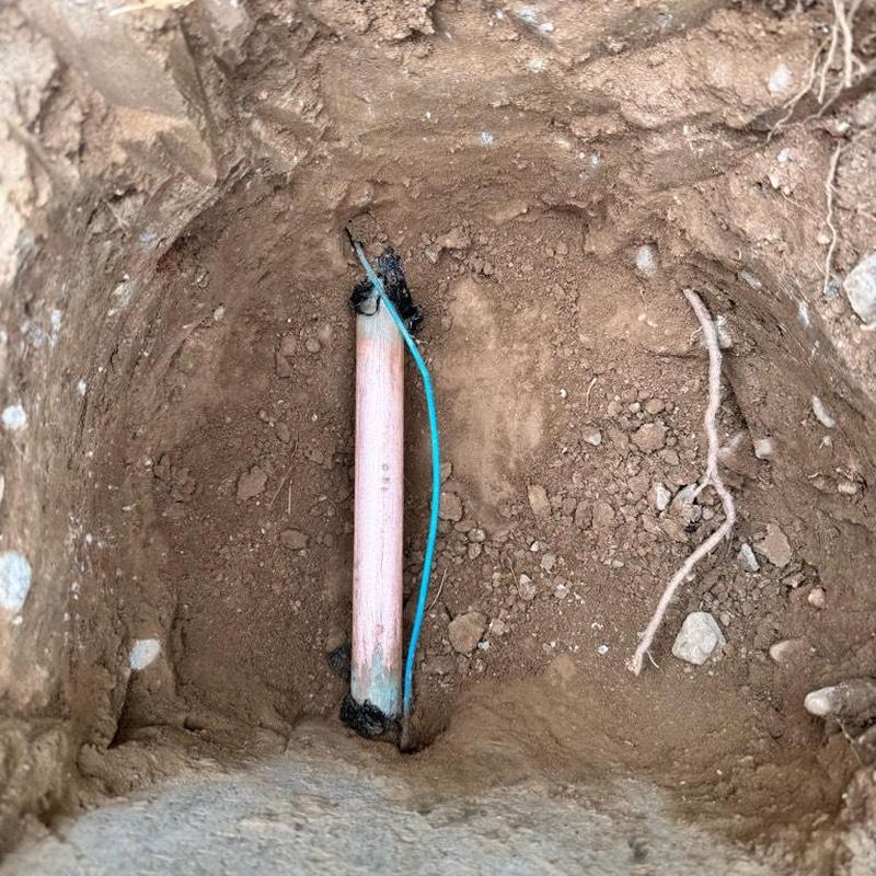 Copper water main pipe with grounding wire in dirt hole