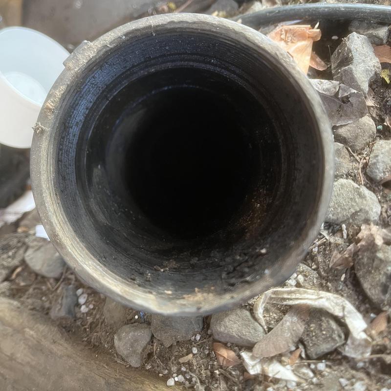 4-inch sewer drain line opening amid dirt and debris