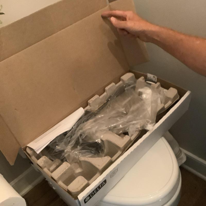 Delta sink faucet in packaging on toilet seat Delta sink faucet in packaging on toilet seat