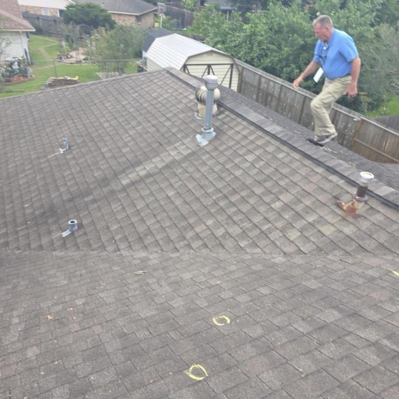 Asphalt shingle roof with hail damage markings and inspector