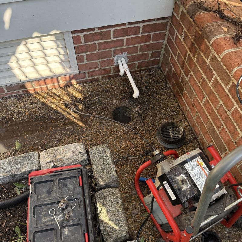 French drain unclogging with plumbing snake tool outside home French drain unclogging with plumbing snake tool outside home