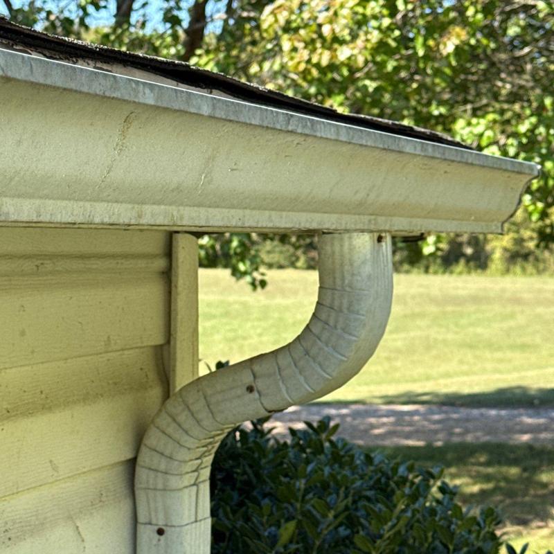 Metal gutter downspout with bent elbow section outdoors
