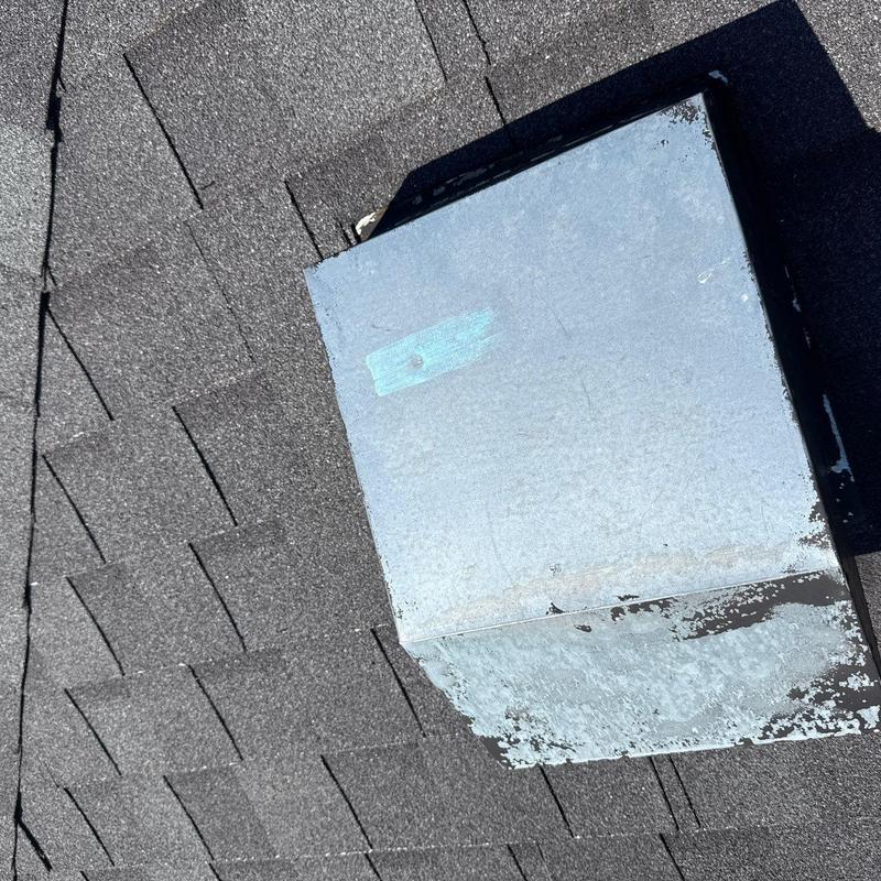Roof vent with peeling paint on asphalt shingles