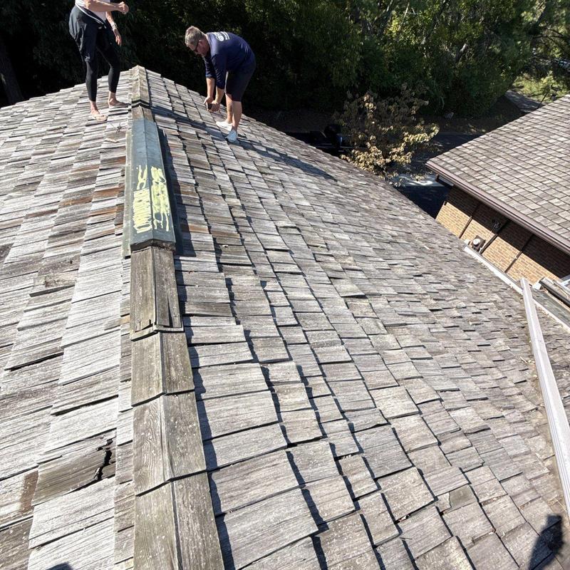 Wood shingle roof inspection showing weather damage