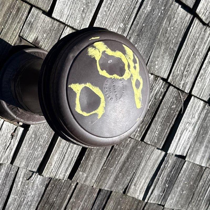 Roof vent with chalk-marked hail damage on shingles