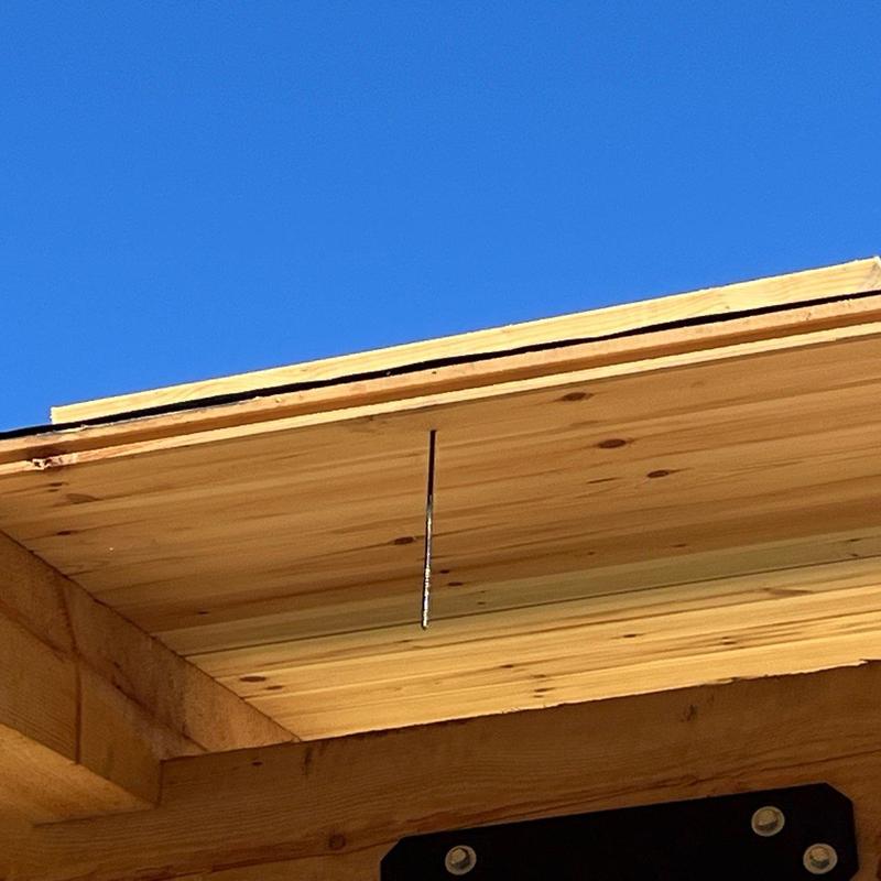 Wooden soffit panel with nail protruding under roof