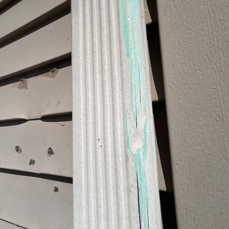 Vinyl siding with hail damage and cracking visible