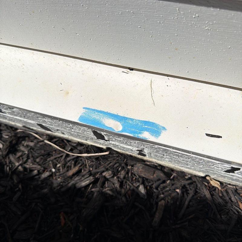 Vinyl siding impact damage with blue marking on panel