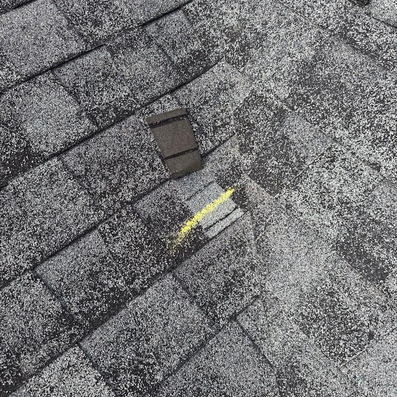 Asphalt shingles with hail damage and yellow chalk mark