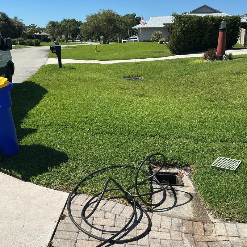 Storm drain jetting with hose on residential lawn