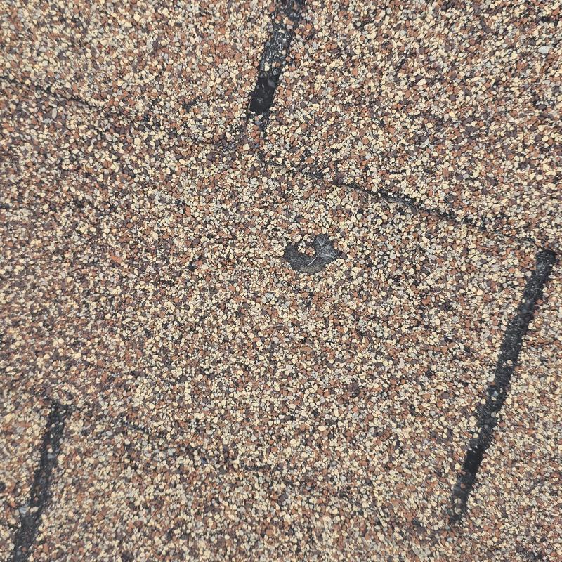 Roof shingle hail damage close-up with marked spots