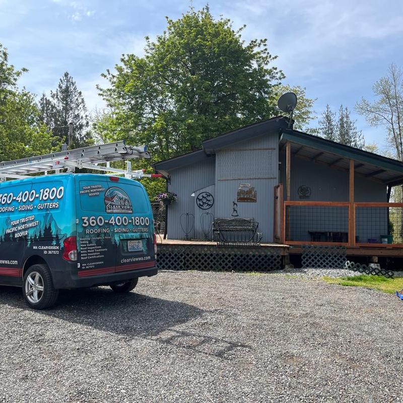 Roof with siding and gutter service van parked nearby