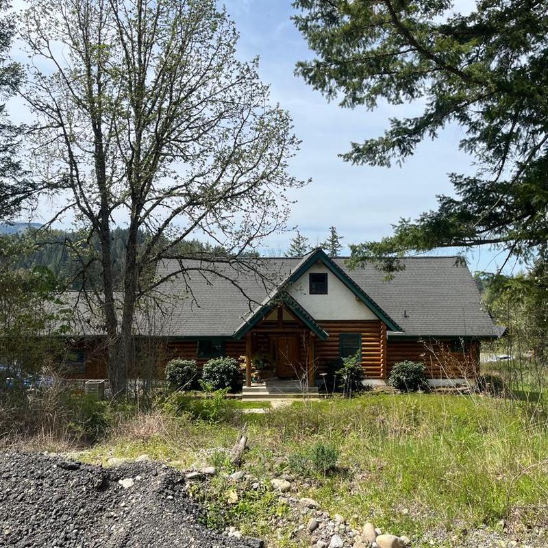 Asphalt shingle roof on log cabin with yard trees