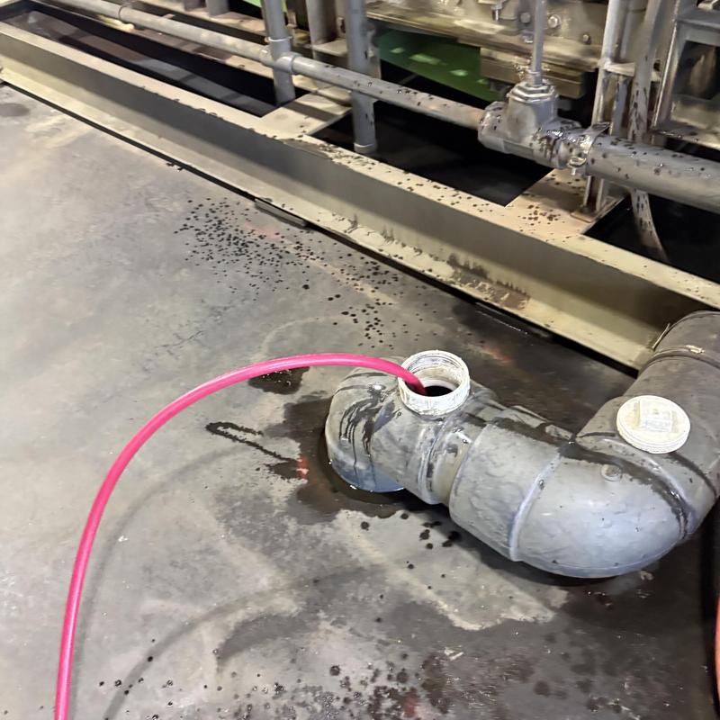 Sanitary line pipe jetting with red hose in industrial area