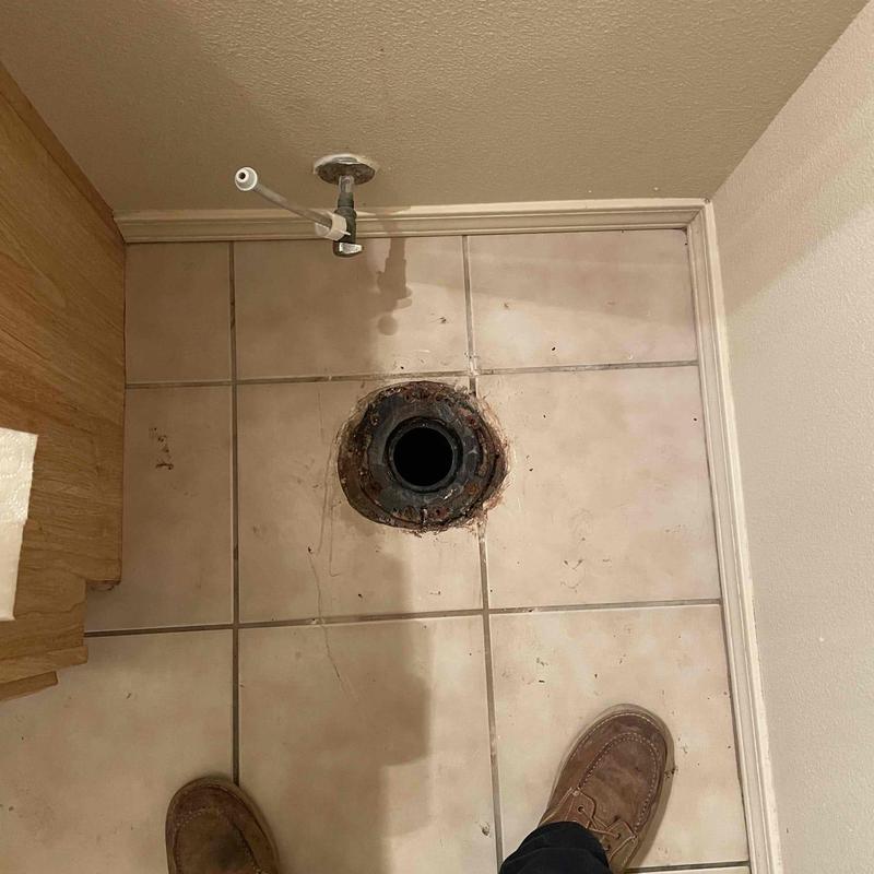 Toilet flange ring on tiled floor before repair