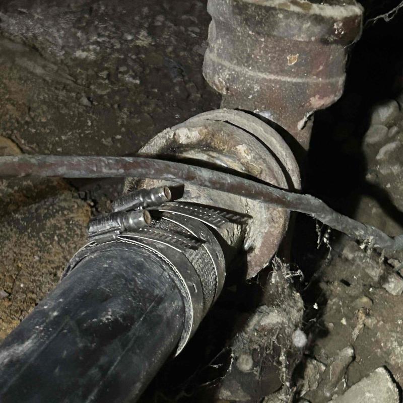Laundry sink drain pipe with hose clamps in crawl space