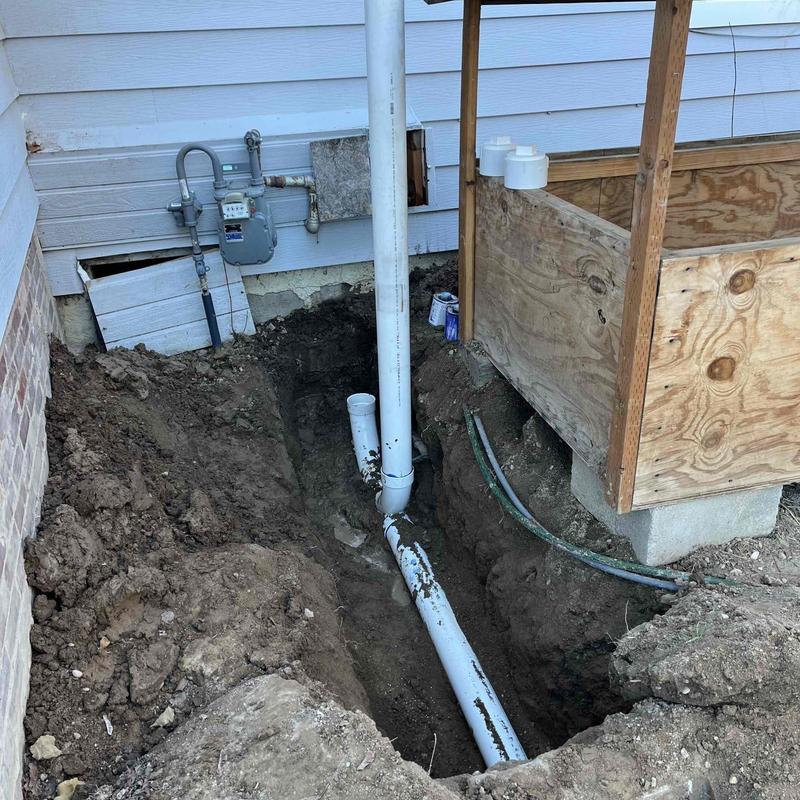 PVC drain pipe installation in ground trench beside house