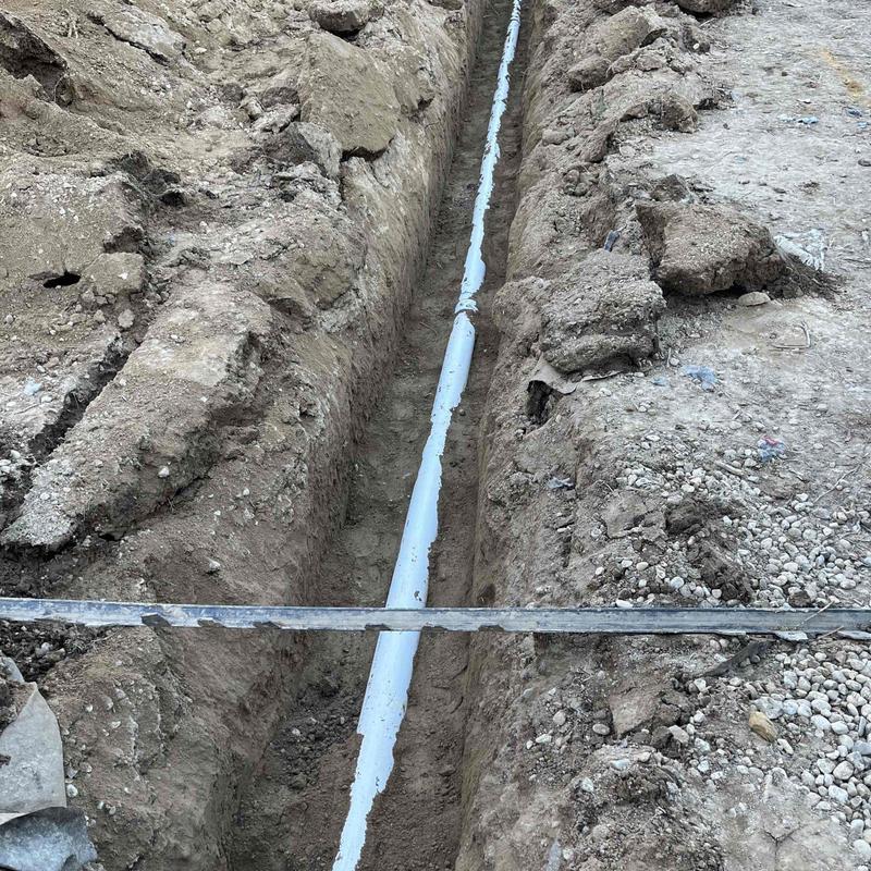 Cesspool pipe installation in narrow dirt trench