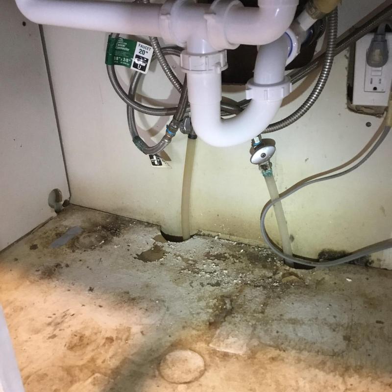Kitchen sink drain pipes with water damage under cabinet