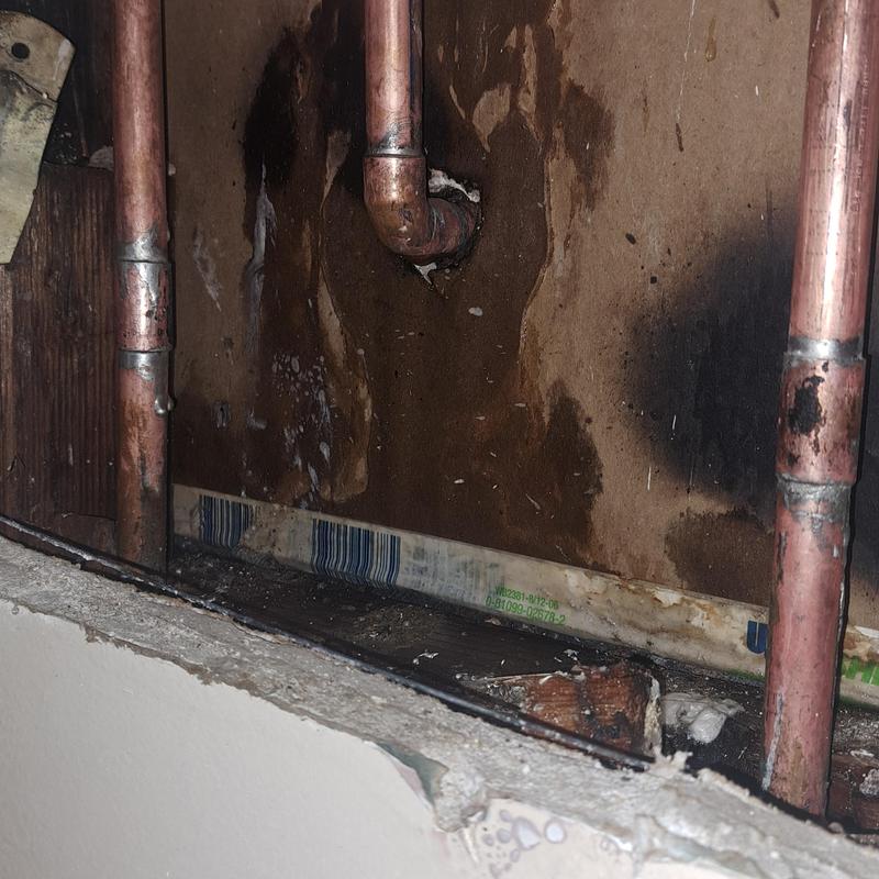 Copper water pipes with wall damage and soot stains