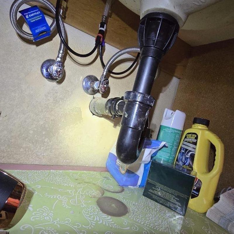 Sink drain pipe with attached water supply lines under cabinet