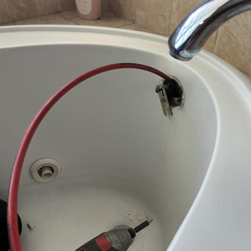 Showertub drain line with snaking cable clearing debris
