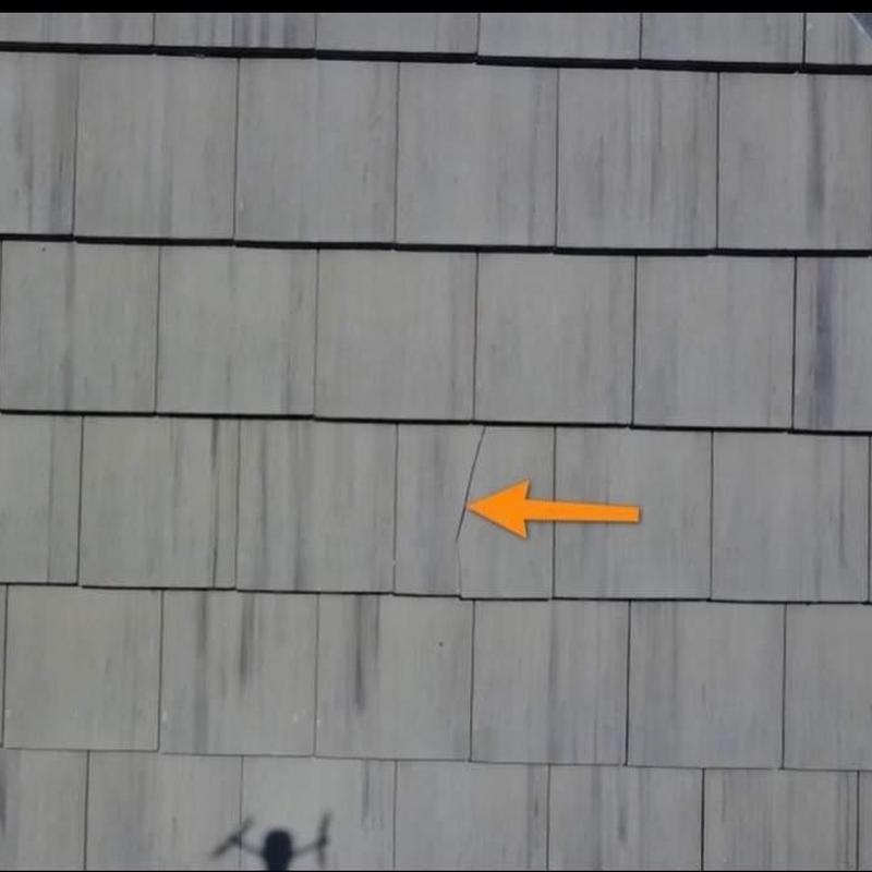 Roof shingles with visible crack marked by arrow