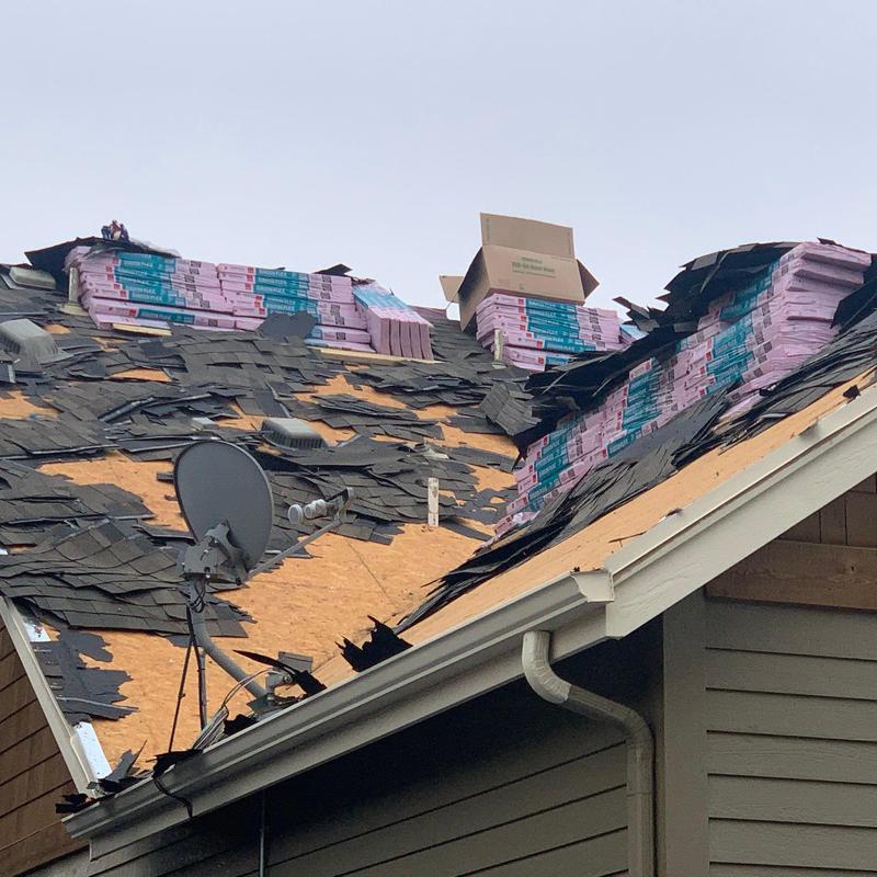 Roof shingle removal with new shingle bundles staged on roof
