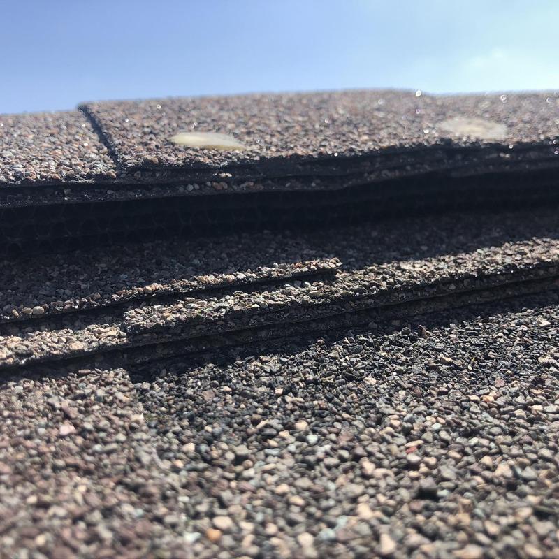 Asphalt shingle roof with lifted and damaged shingles
