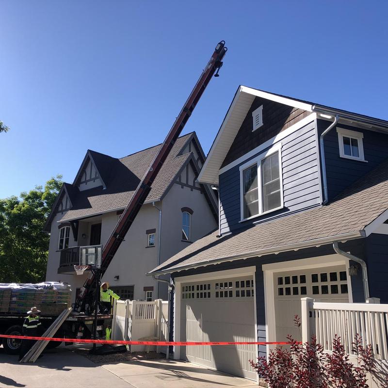 Asphalt shingle roofing installation with crane and crew