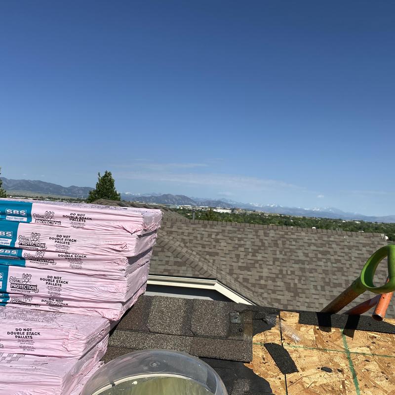 Asphalt shingle roofing materials stacked on roof edge